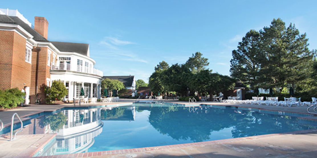 A large swimming pool with a house in the background.