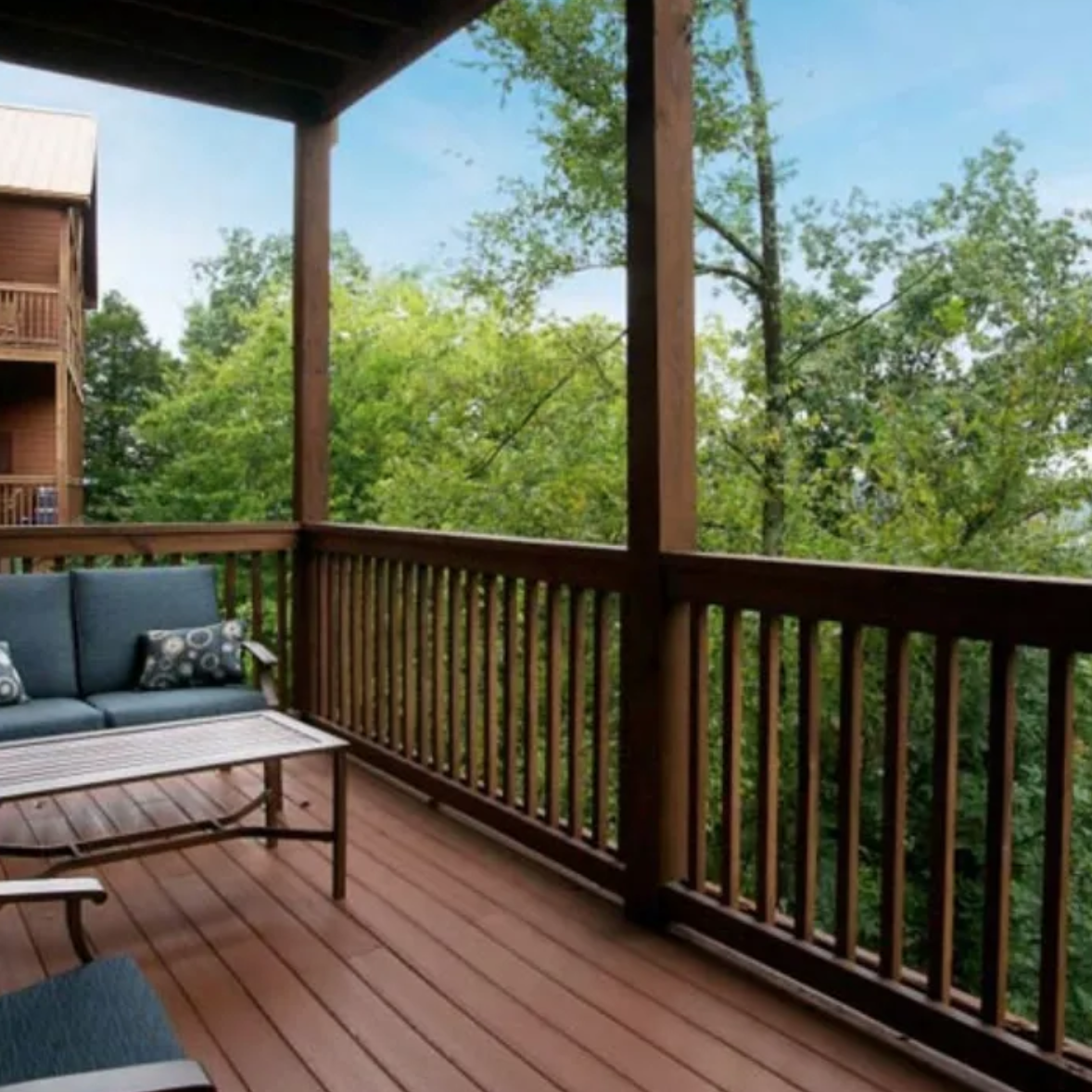 A deck with furniture and trees in the background.